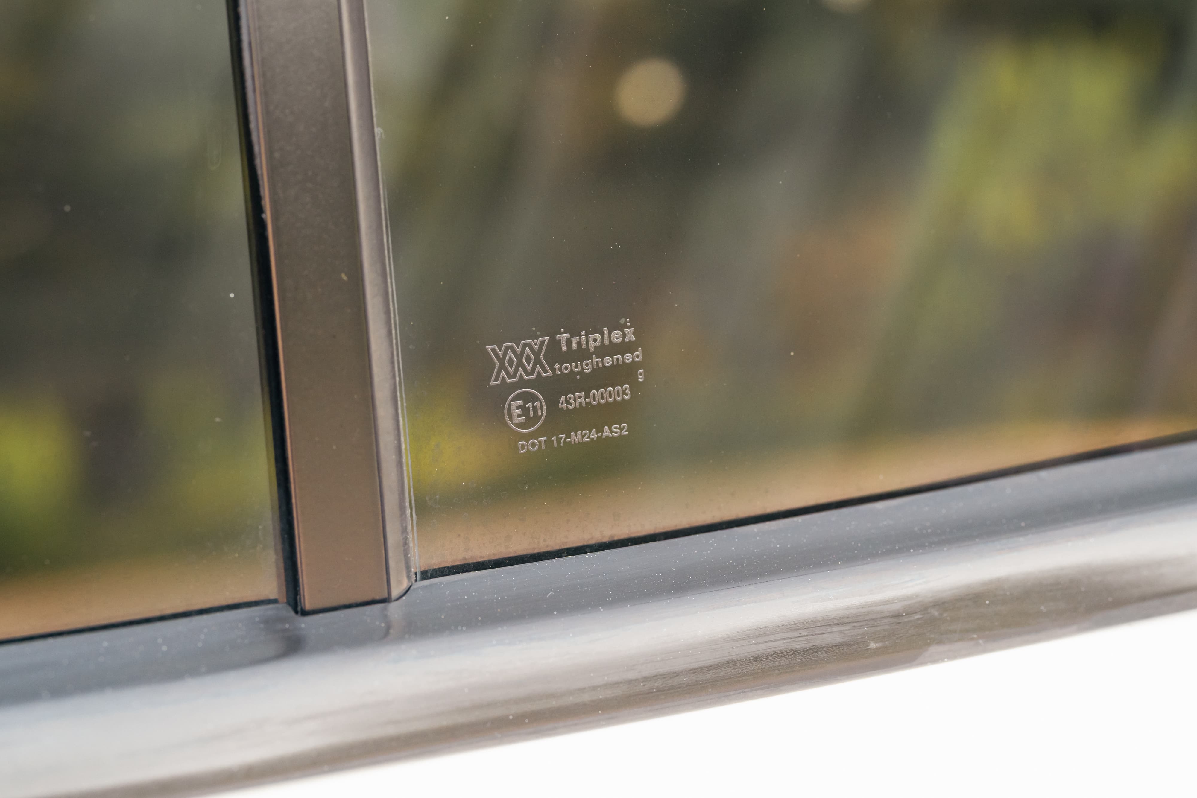 Close-up of a white 1995 Land Rover Range Rover County side window with Triplex toughened glass marking.