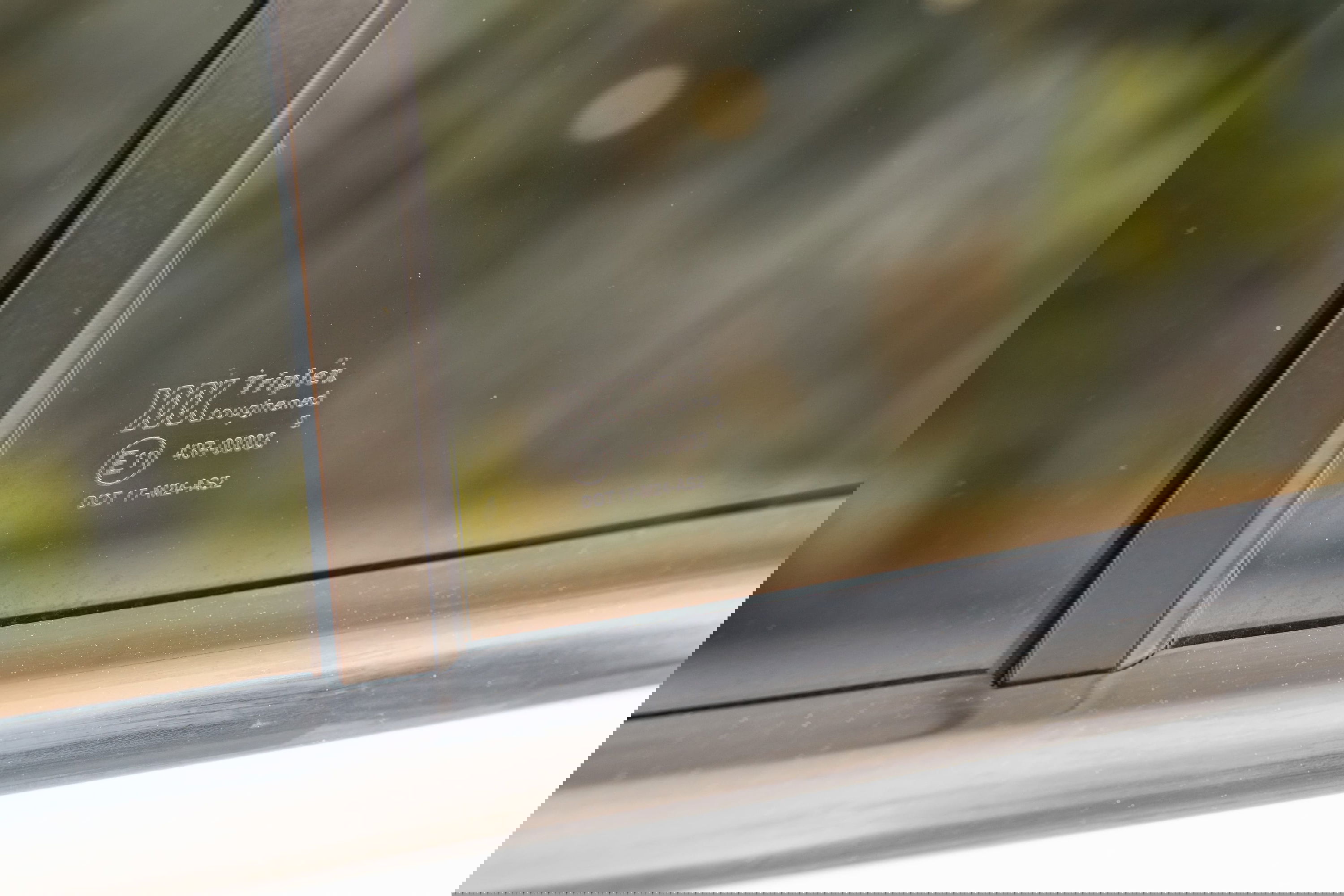 Close-up of a white 1995 Land Rover Range Rover County side window with Triplex toughened glass marking.