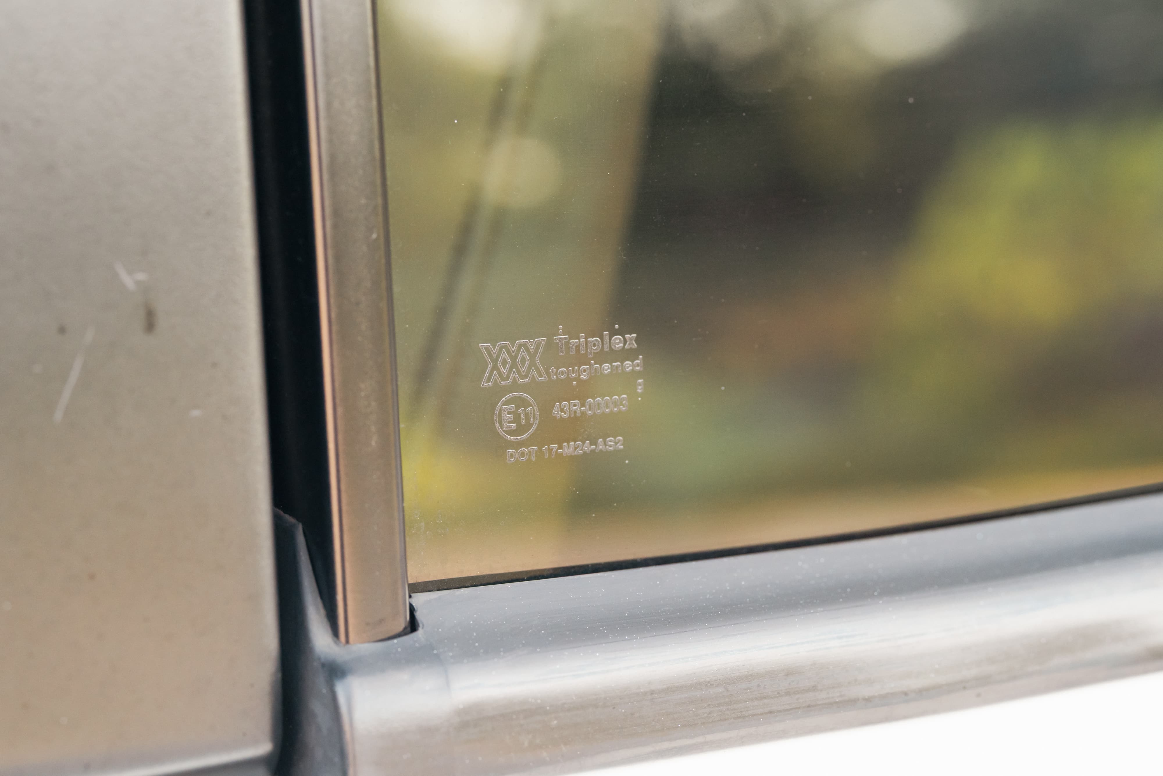 Close-up of 1995 white Range Rover side window with Triplex laminated glass markings.