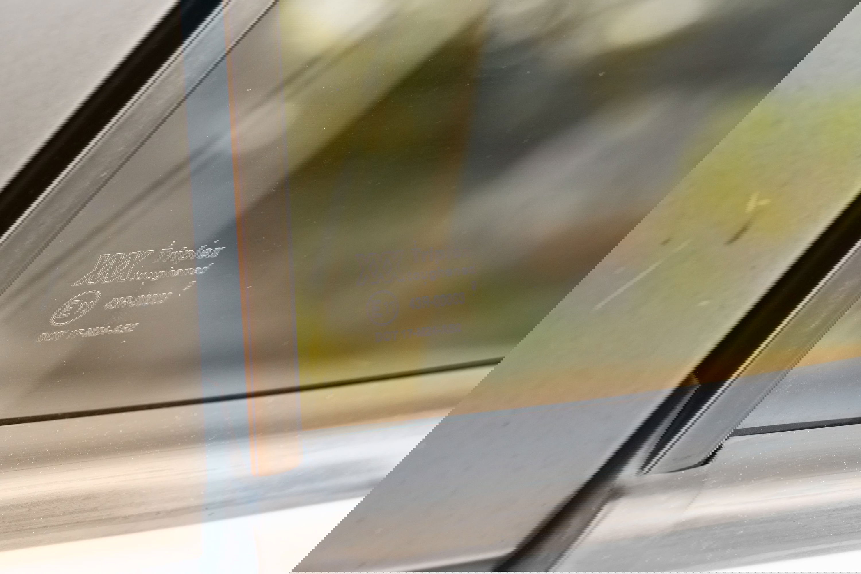 Close-up of 1995 white Range Rover side window with Triplex laminated glass markings.