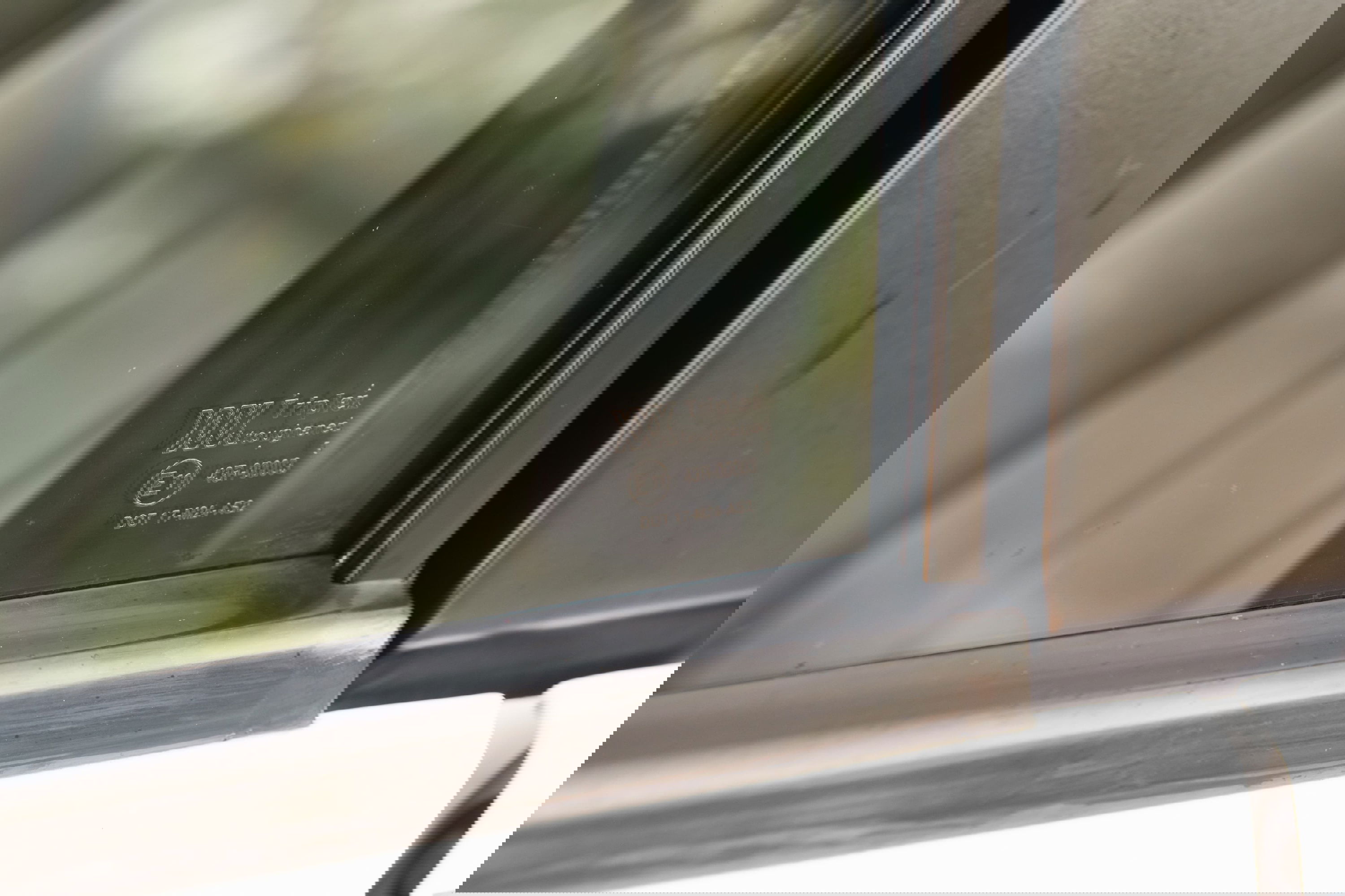 Close-up on the driver's side window of a white 1995 Range Rover County, showing toughened glass markings.