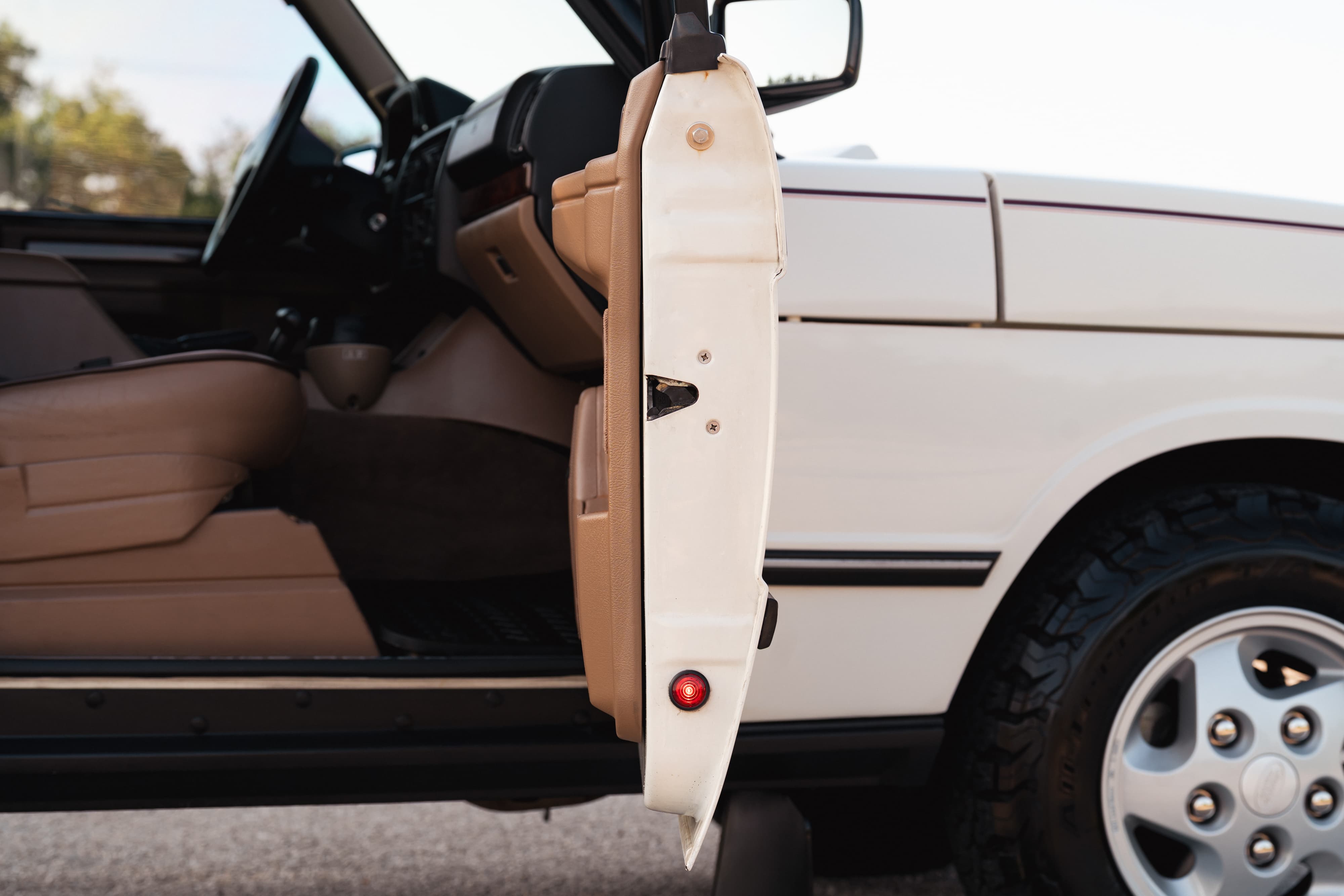 White 1995 Range Rover County with open driver door, tan interior, and alloy rims.