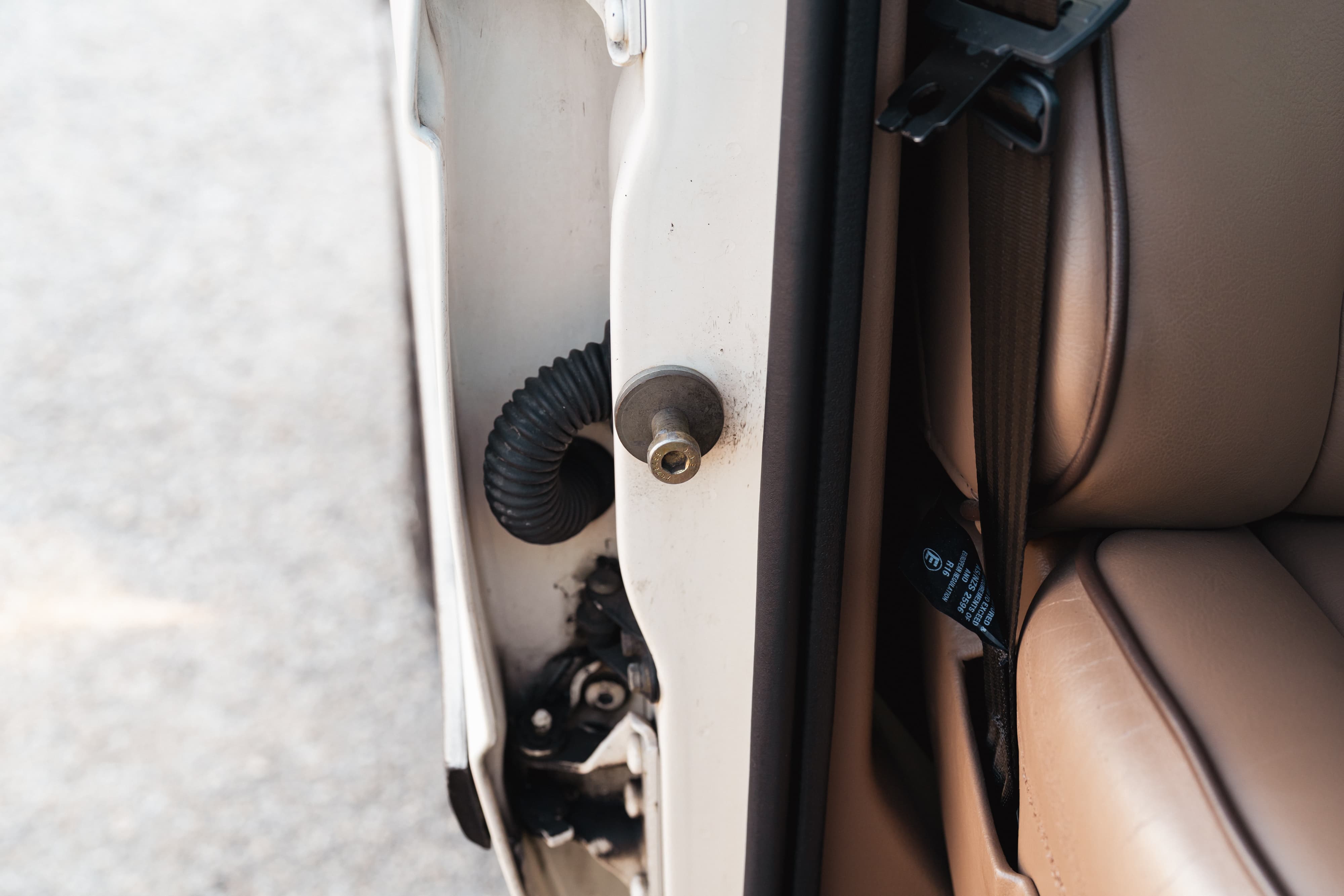 1995 white Range Rover County door jamb with beige leather seat and seatbelt.