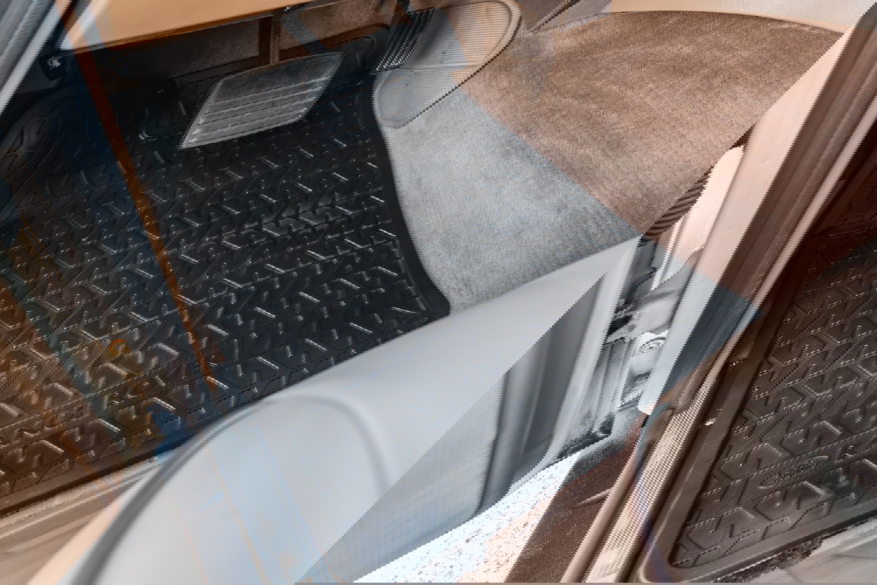 Black Range Rover floor mats with a tire tread pattern on beige carpet.