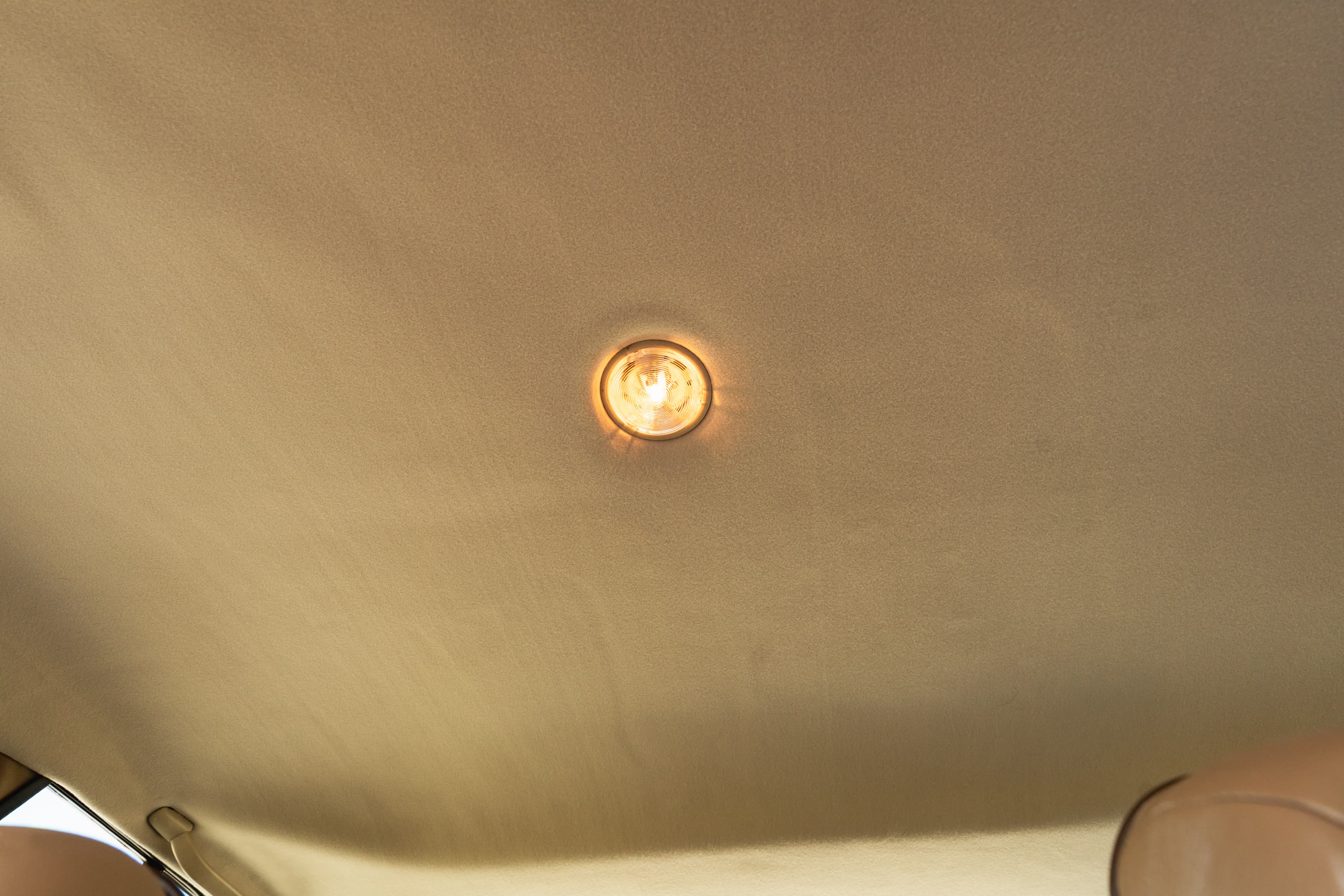 Interior shot of a 1995 Land Rover Range Rover County with a beige headliner and illuminated dome light.