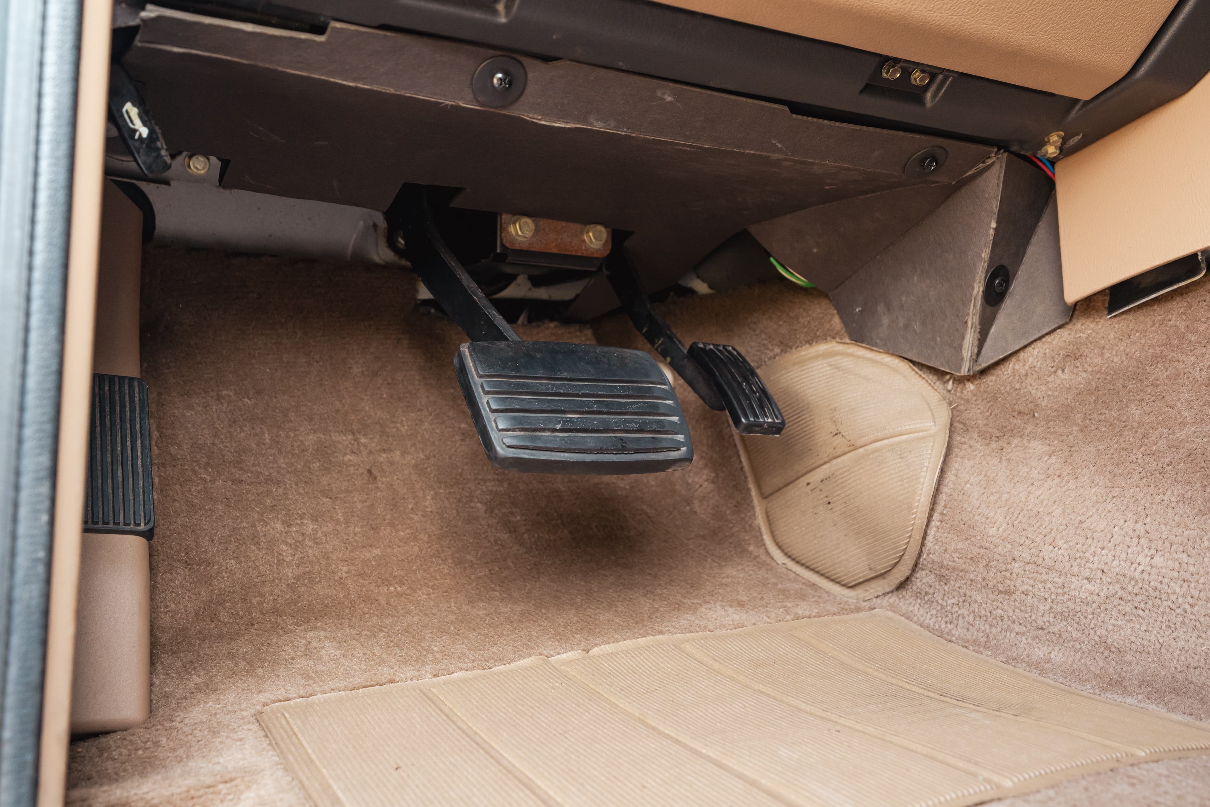 1995 Land Rover Range Rover footwell with brake and clutch pedals, tan carpet, and floor mats.