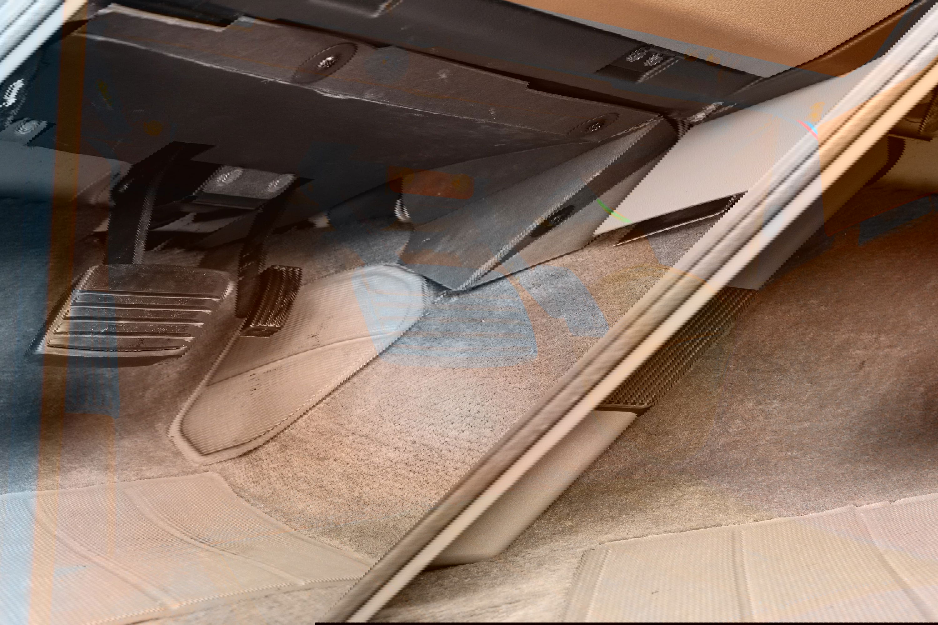 1995 Land Rover Range Rover footwell with brake and clutch pedals, tan carpet, and floor mats.