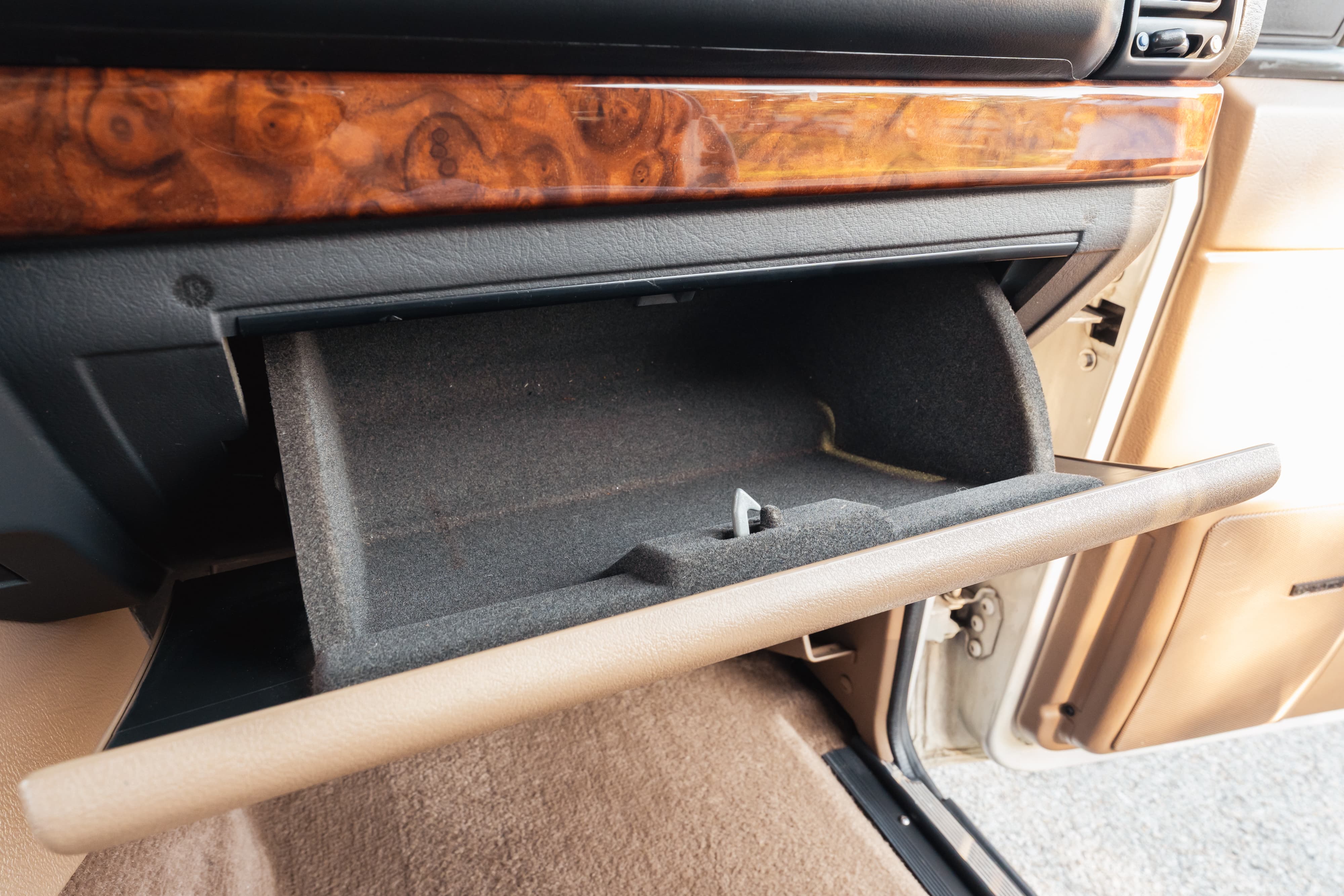 1995 Range Rover County open glove box with wood trim and beige interior.