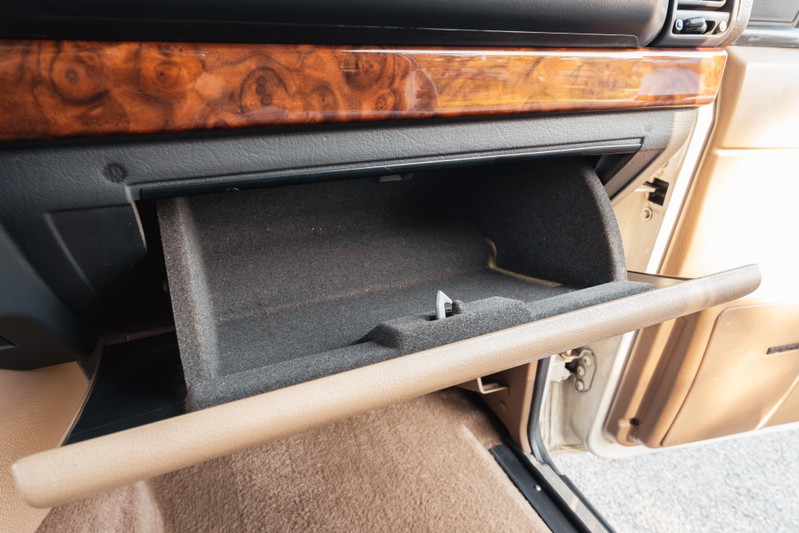1995 Range Rover County open glove box with wood trim and beige interior.
