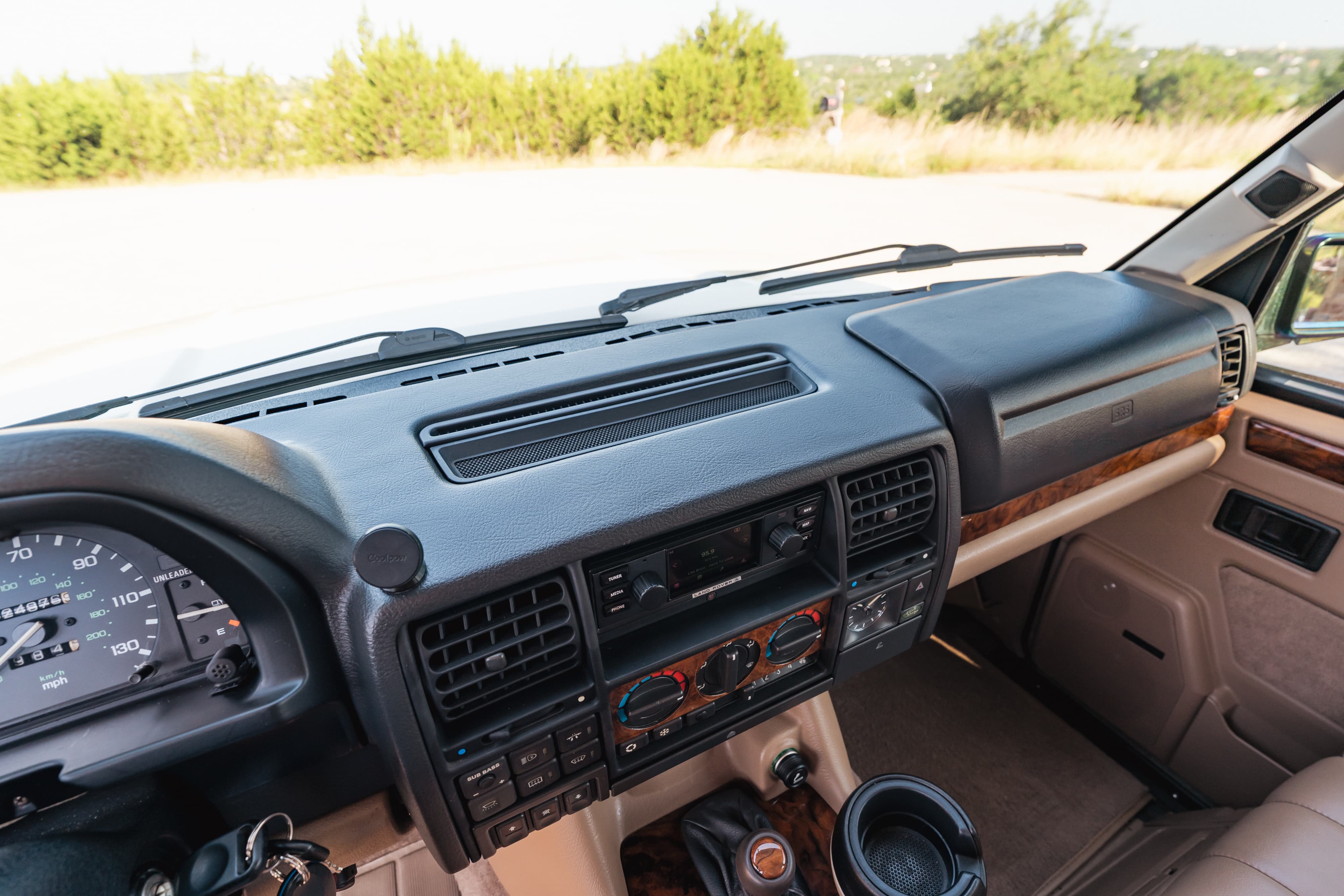 Interior dashboard of a white 1995 Land Rover Range Rover County with wood trim and tan upholstery.