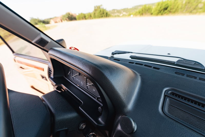 Interior view of a white 1995 Land Rover Range Rover County dashboard with analog gauges and wood trim.