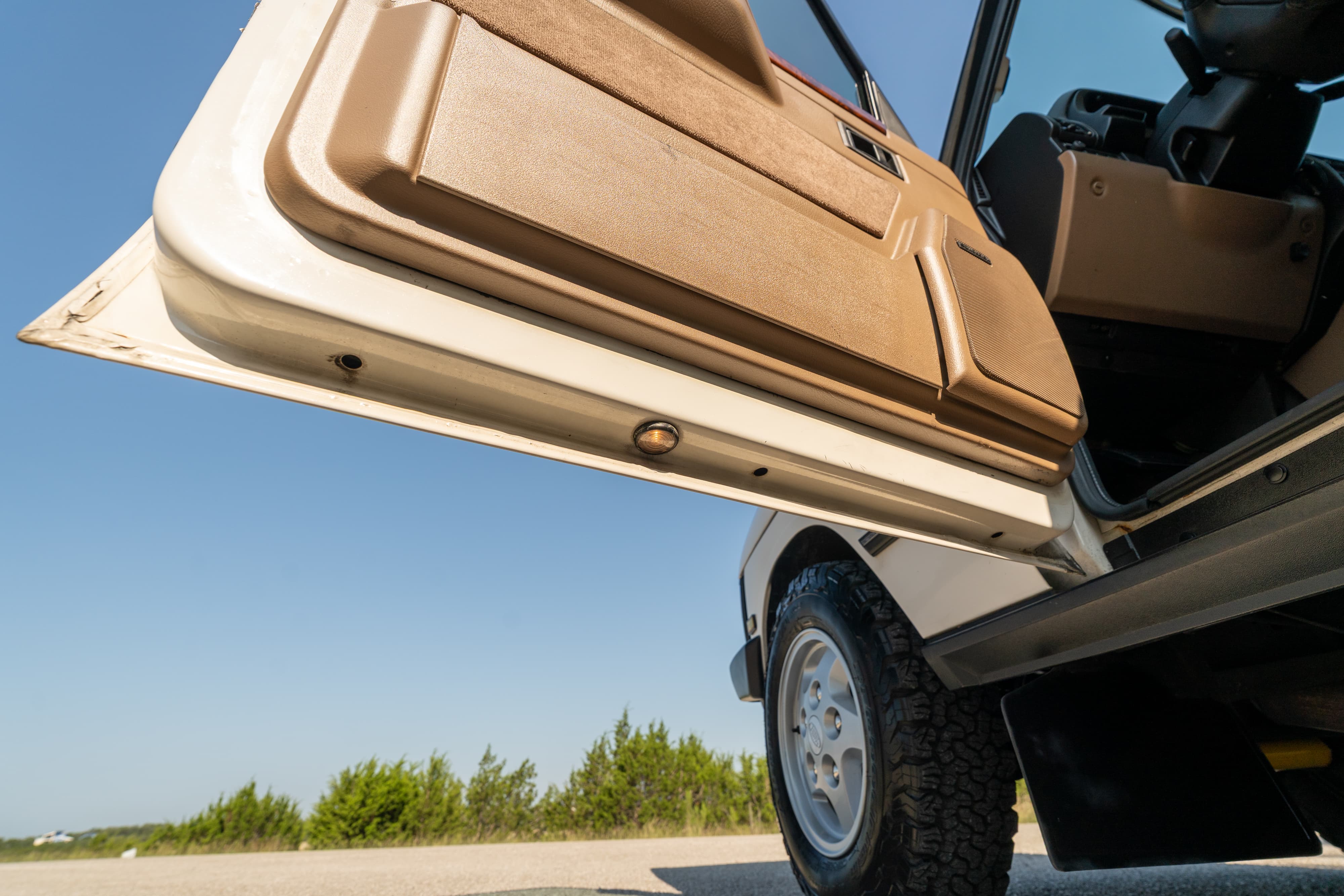 1995 white Land Rover Range Rover County door open, showing tan trim and wheel.