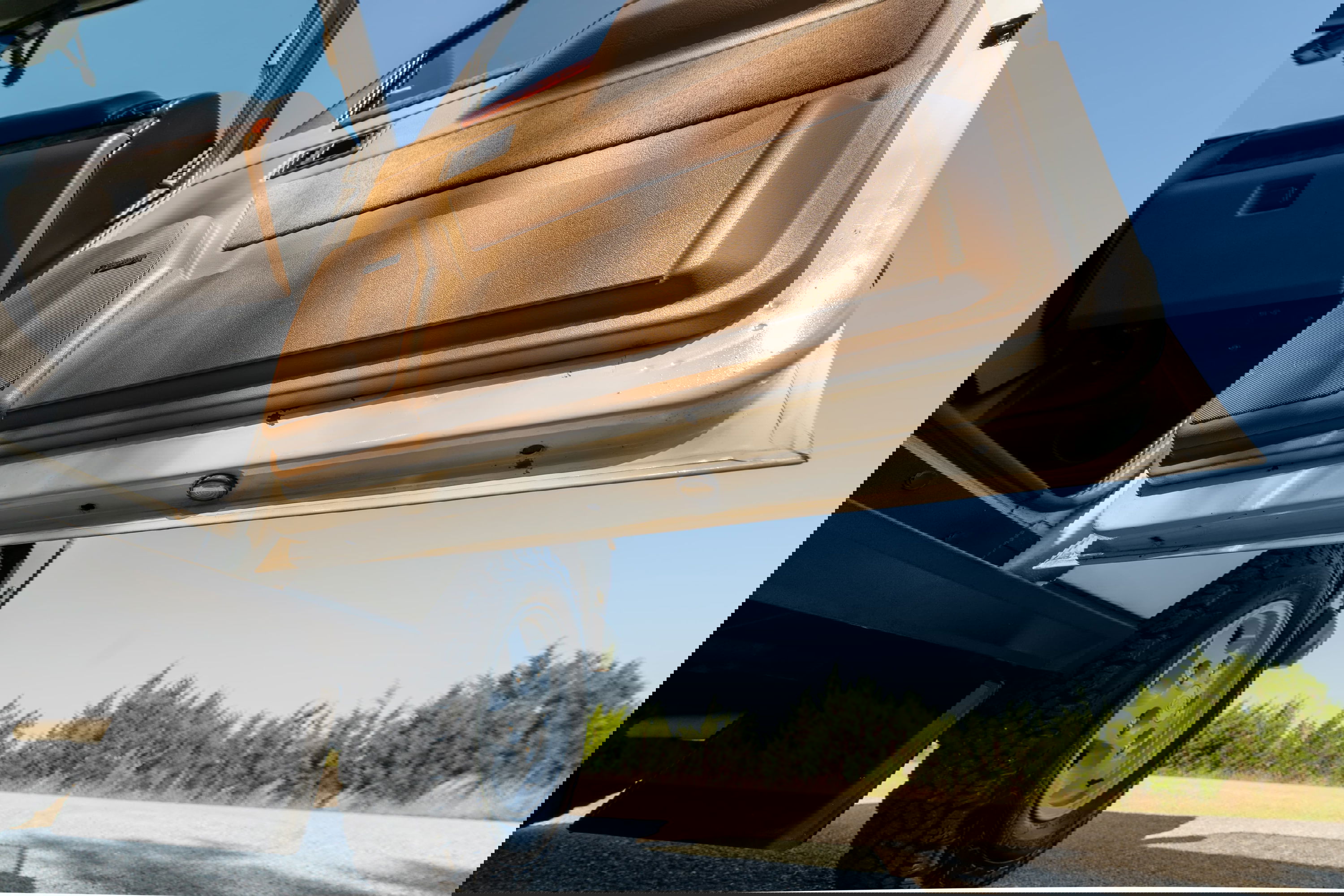 1995 Range Rover County door open, showing tan trim, and off-road tire with classic rims.