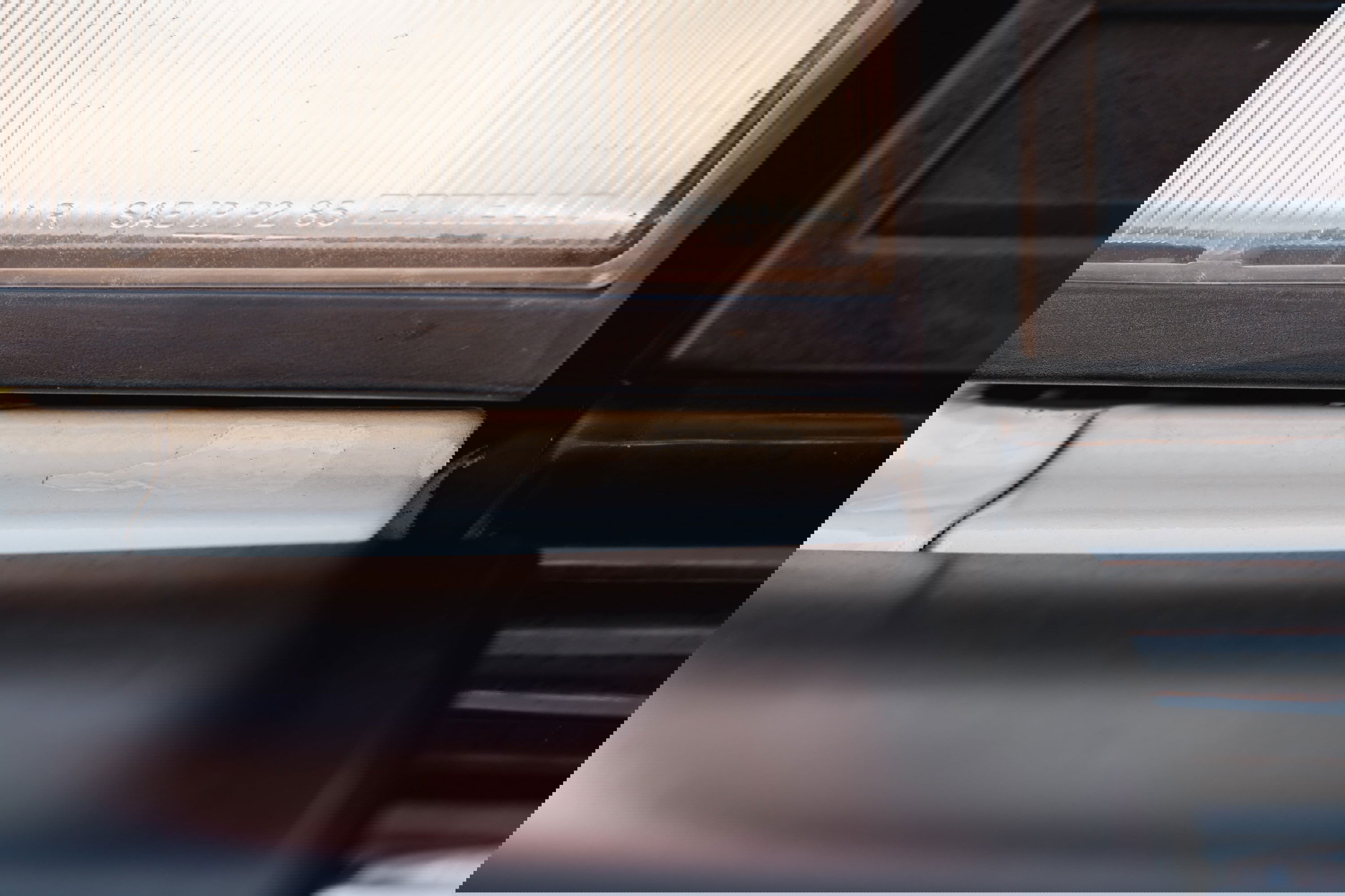 Close-up of a white 1995 Land Rover Range Rover County's headlight trim and dark bumper trim.