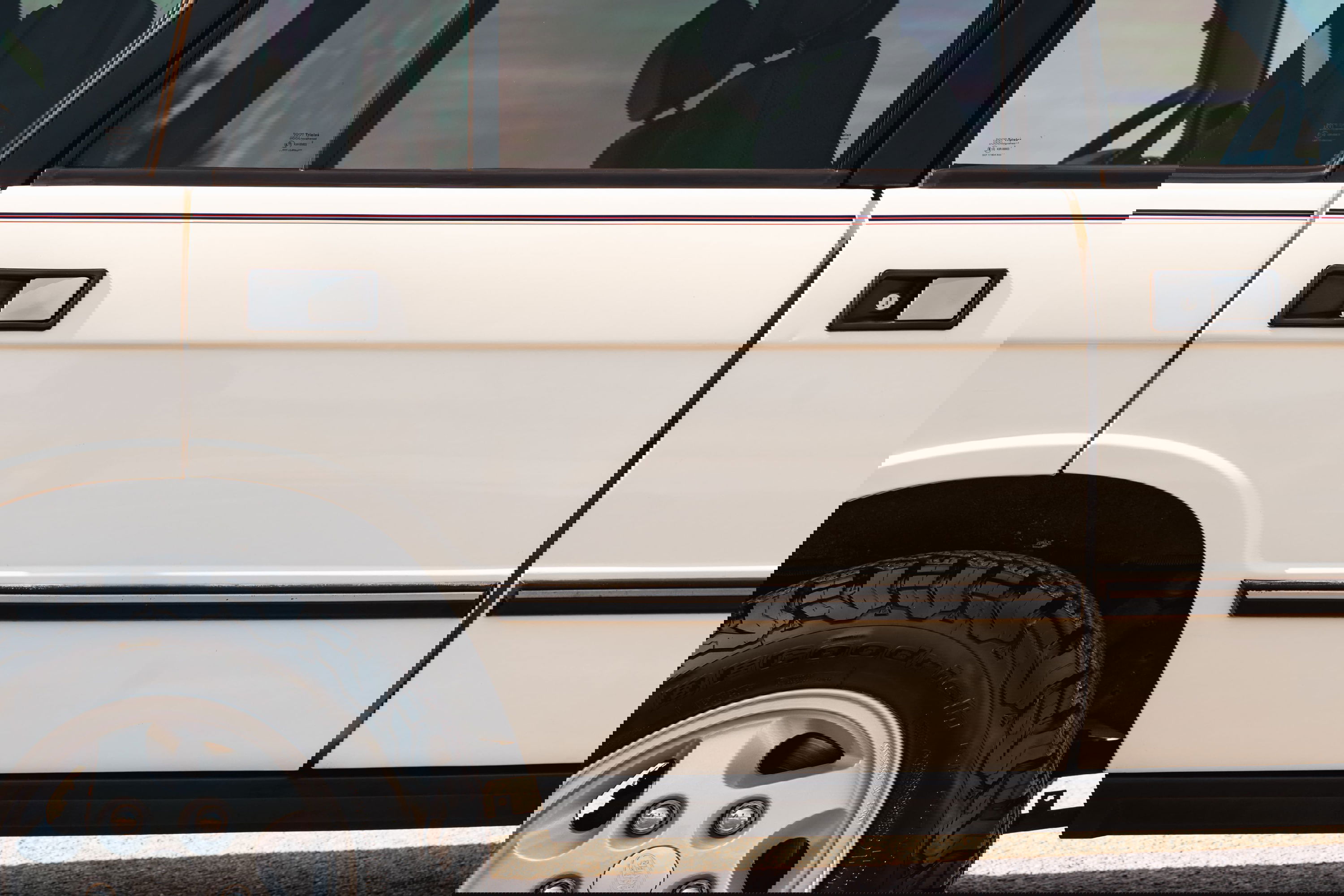 White 1995 Land Rover Range Rover County: detail of door handles, black trim, and alloy rim.