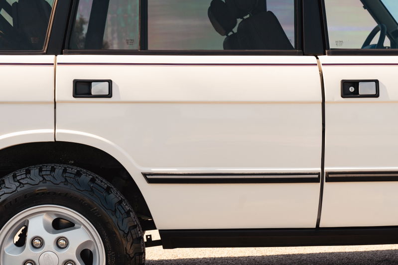 White 1995 Land Rover Range Rover County: detail of door handles, black trim, and alloy rim.