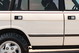 White 1995 Land Rover Range Rover County: detail of door handles, black trim, and alloy rim.