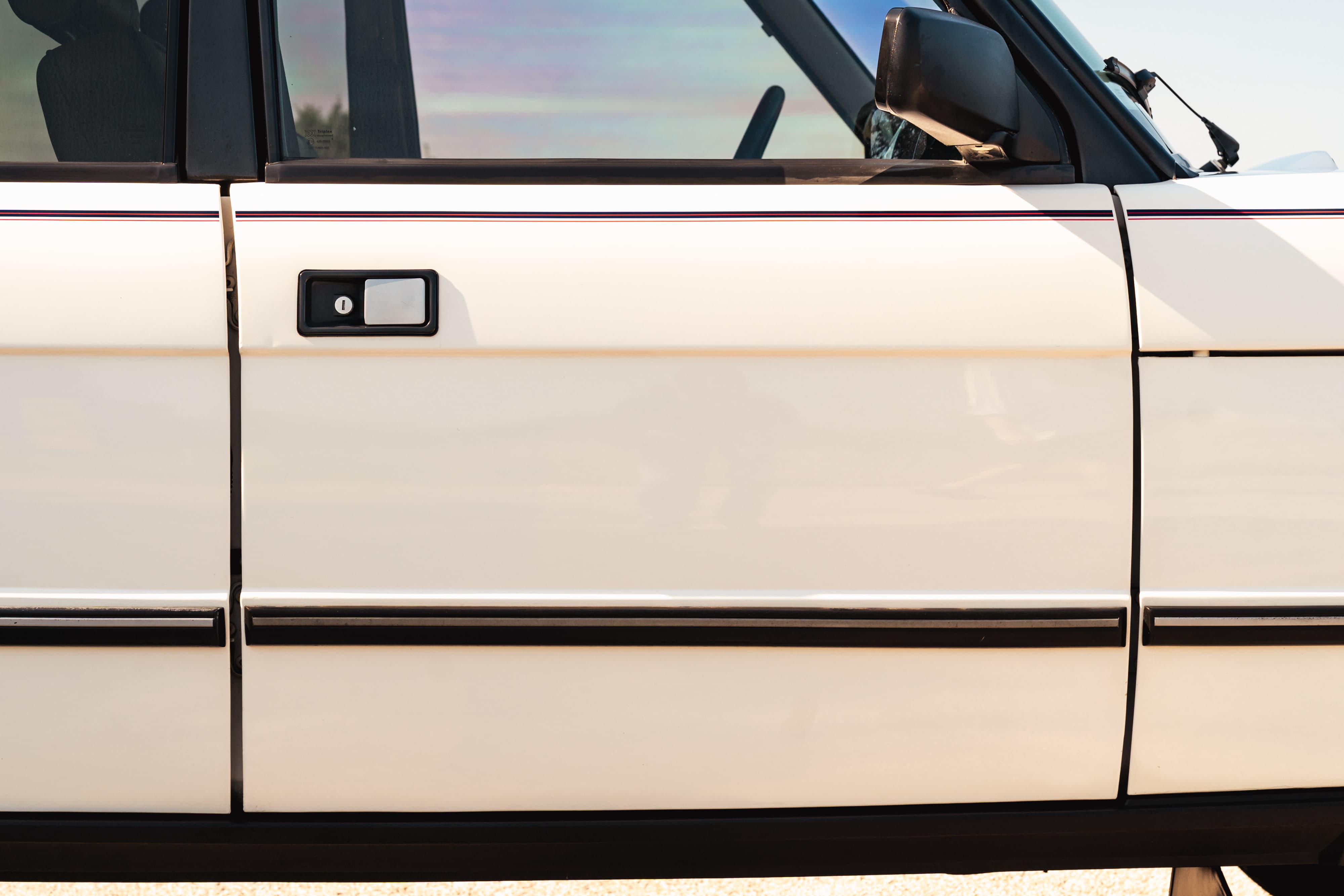 White 1995 Range Rover County side door with black trim and a burgundy pinstripe detail.