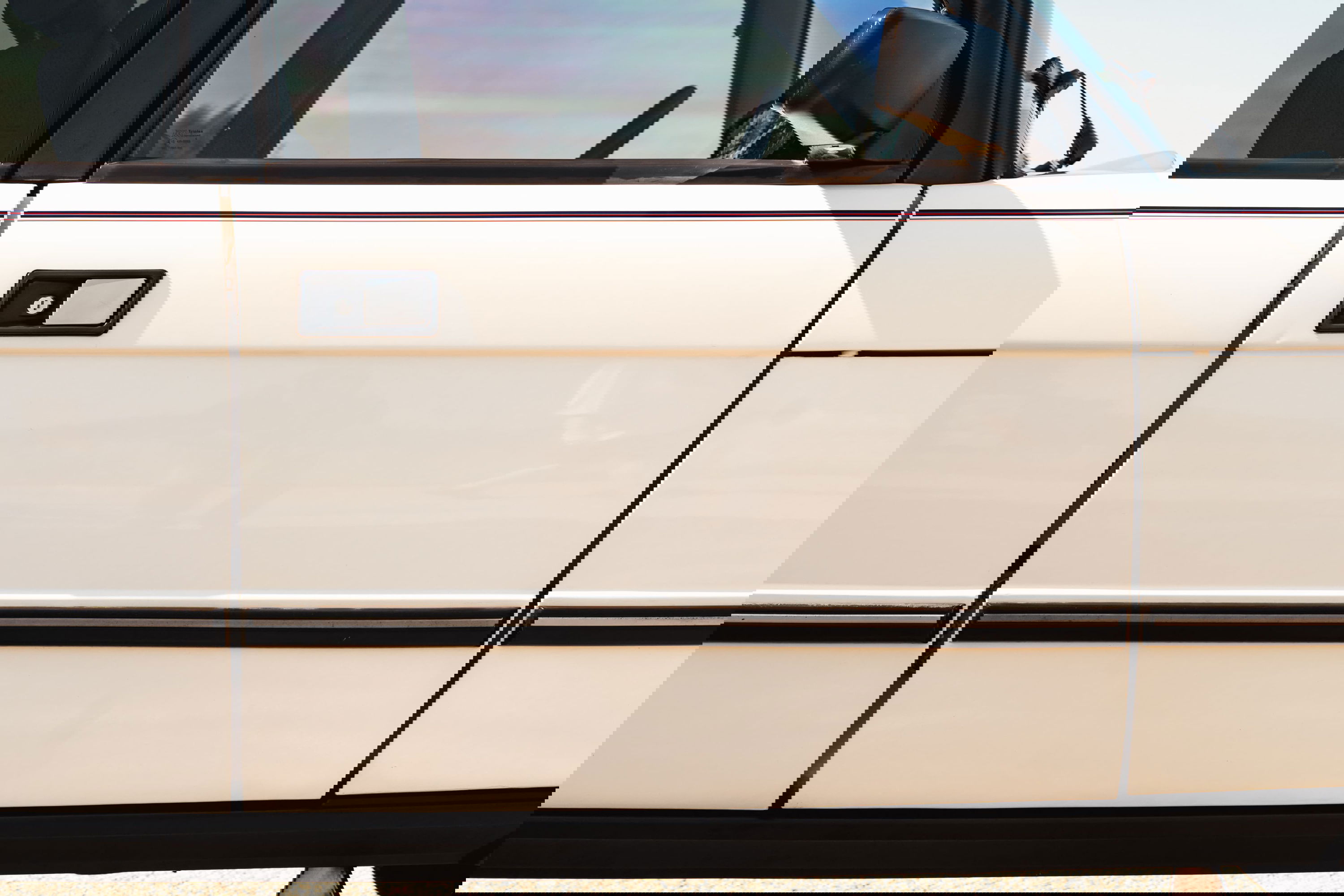 White 1995 Range Rover County side door with black trim and a burgundy pinstripe detail.