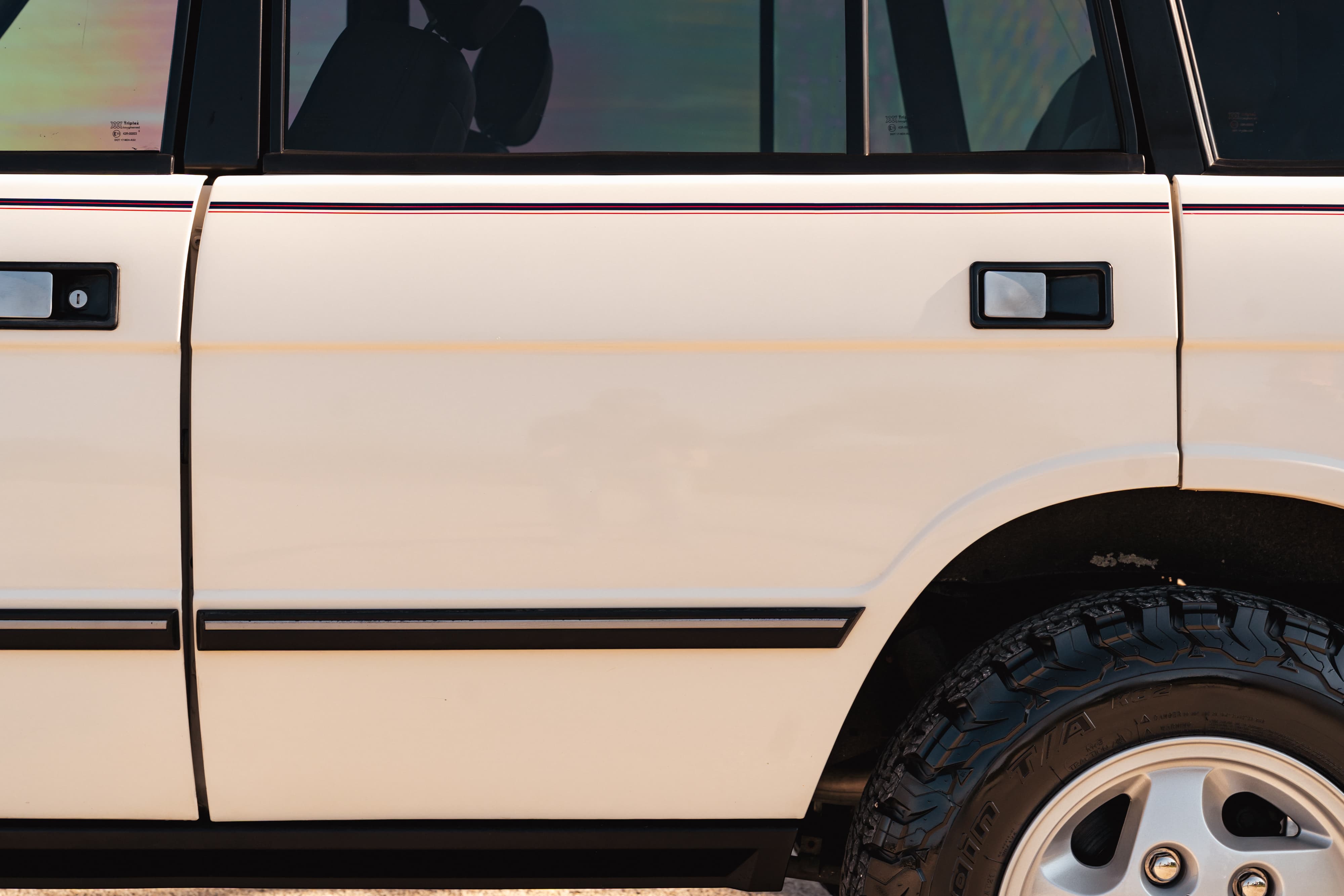 White 1995 Range Rover County side door with black and maroon trim, silver rims.