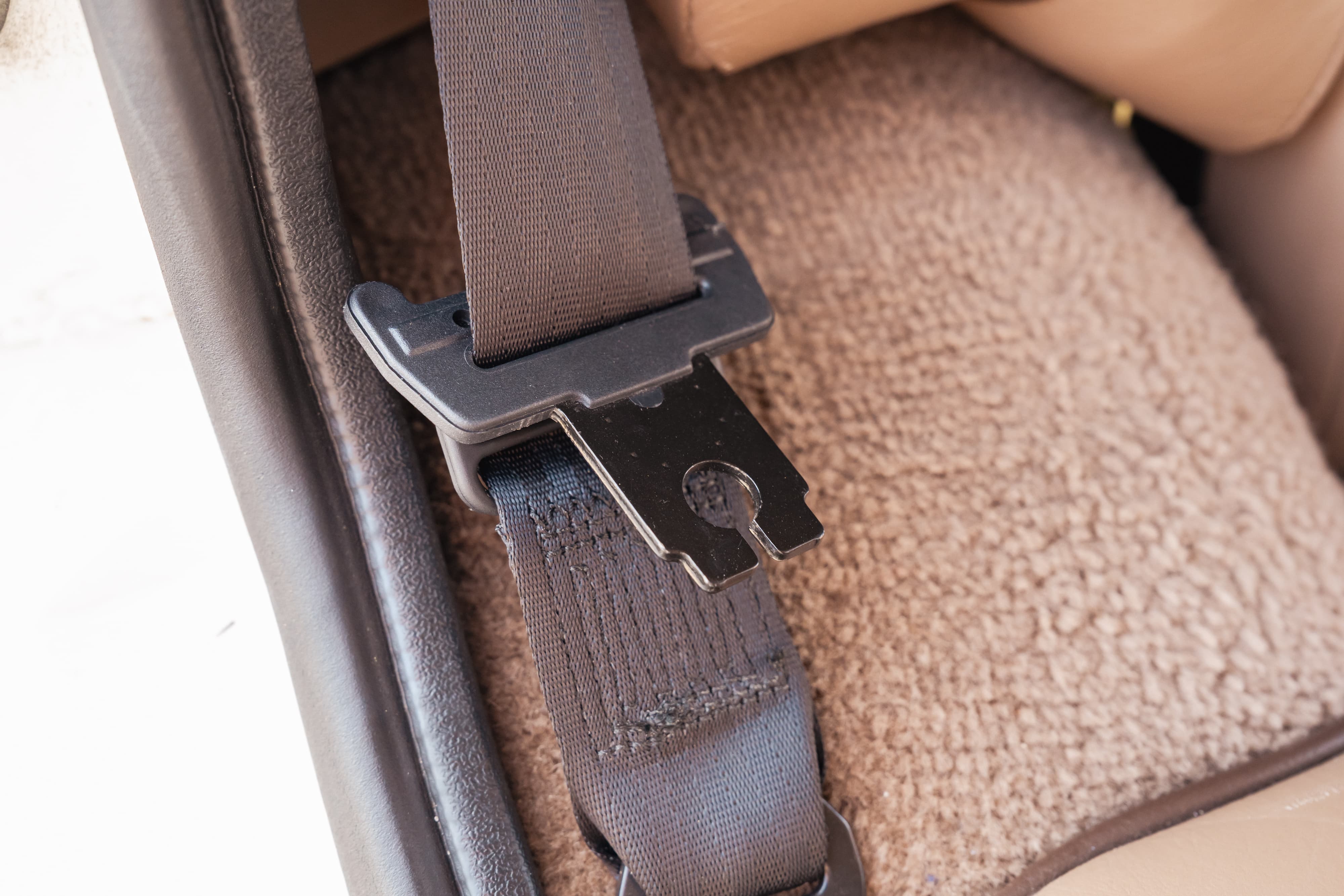 1995 white Land Rover Range Rover County seatbelt buckle and tan carpet.