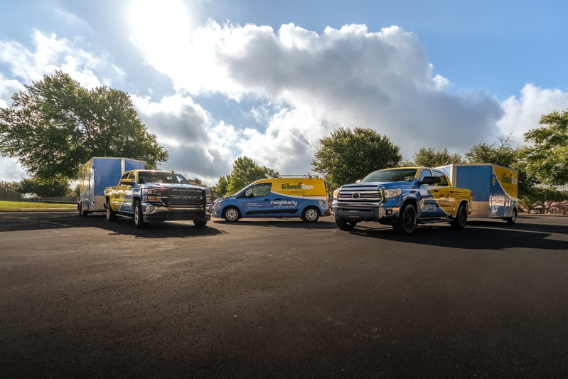 Two blue & yellow Trucks towing trailers, a blue van with livery. Trucks have unique livery.