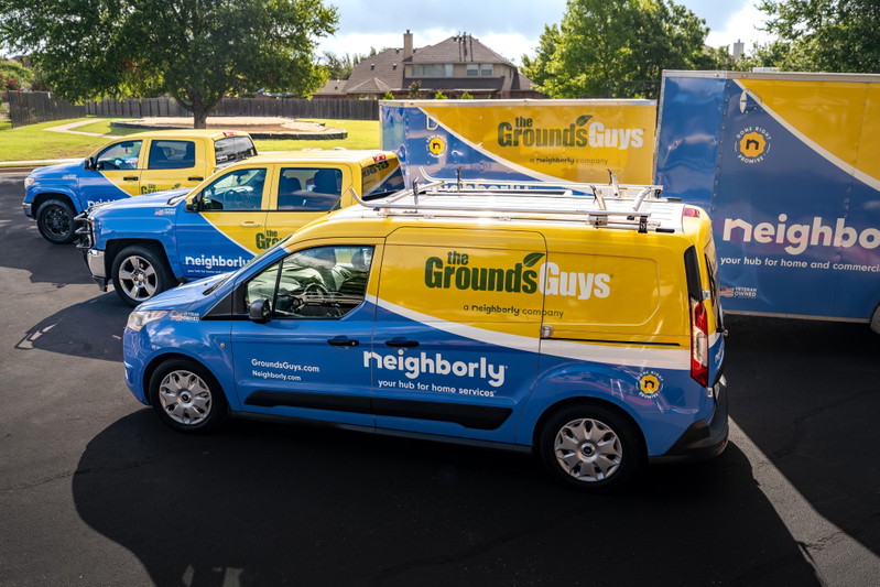 A blue and yellow Ford Transit Connect van with Neighborly livery, featuring silver rims.