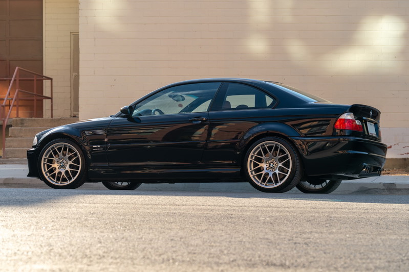 Side profile of a black 2002 BMW M3 coupe with silver multi-spoke rims.