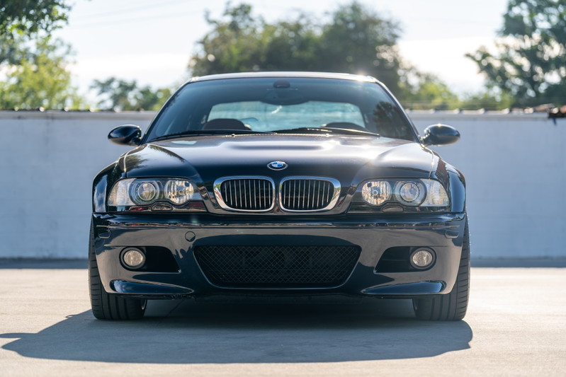 Front view of a carbon black 2002 BMW M3 with chrome grille and clear headlights.