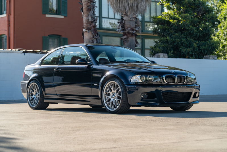 A black 2002 BMW M3 coupe with silver multi-spoke rims and M badging.