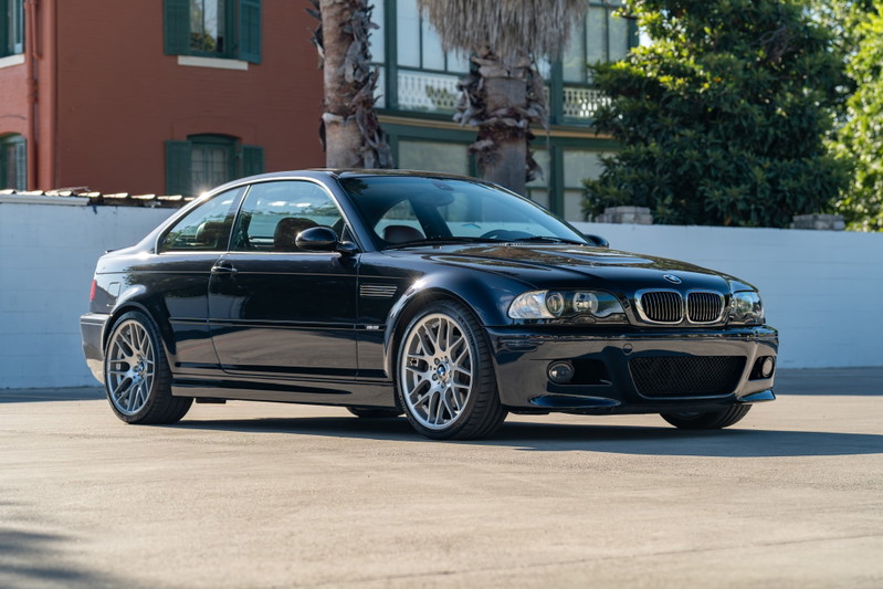 A black 2002 BMW M3 coupe with silver multi-spoke rims and M badging.