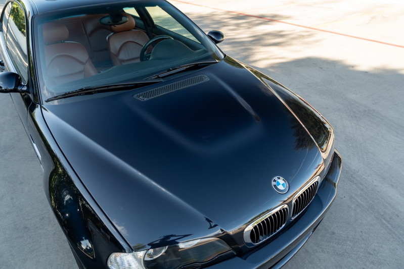 Carbon Black 2002 BMW M3 coupe with tan leather interior, hood scoop, and chrome grille.