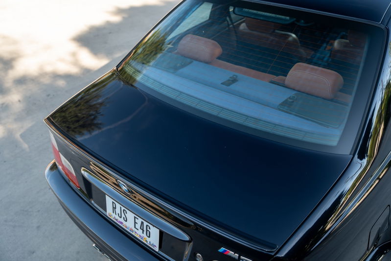 Black 2002 BMW M3 E46 trunk with chrome trim and red interior headrests.