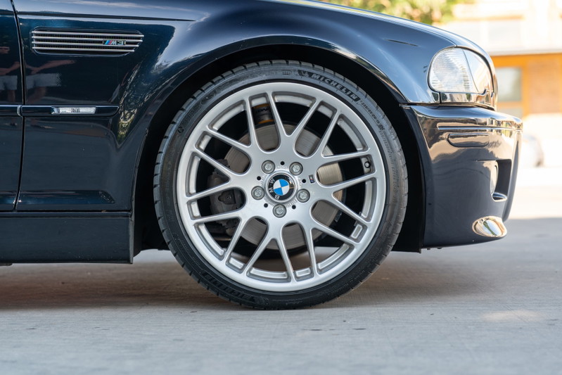 Carbon black 2002 BMW M3 front wheel with silver alloy rims and M badging.