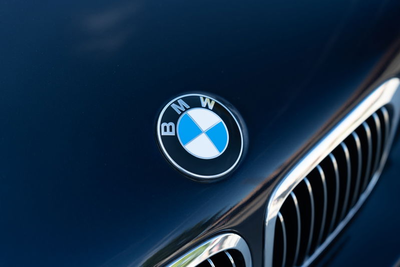 Close up of the BMW emblem on a carbon black 2002 BMW M3 hood, with chrome grille trim.