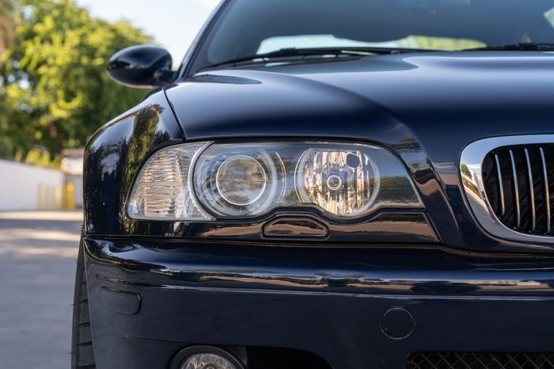 Carbon black 2002 BMW M3 headlight detail with chrome grille trim.