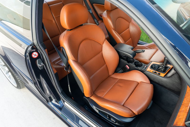Carbon black 2002 BMW M3 coupe with tan leather sport seats and wood trim interior.