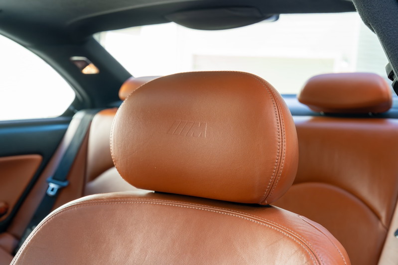 Brown leather M3 interior with embossed M logo on headrest. 2002 BMW M3 cabin detail.