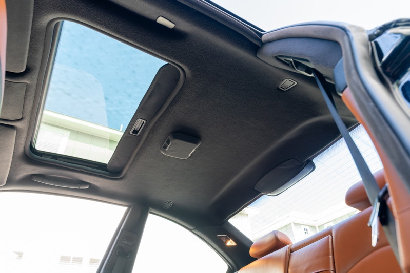 Interior shot of a 2002 BMW M3 with a sunroof open and tan leather seats.