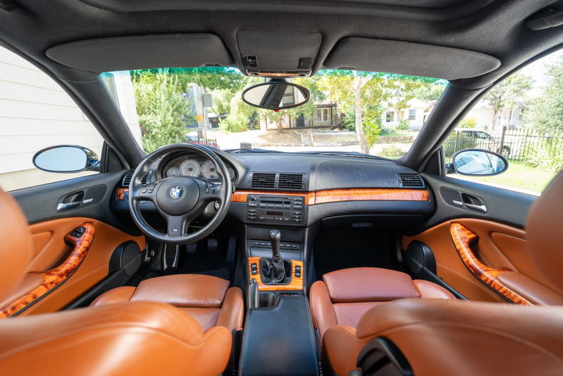Interior of a black 2002 BMW M3 with tan leather seats and wood trim.