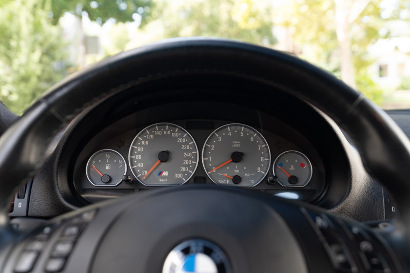 2002 BMW M3 instrument cluster with analog gauges and M logo.