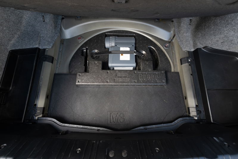2002 BMW M3 trunk features a compact spare tire kit and M logo trim.