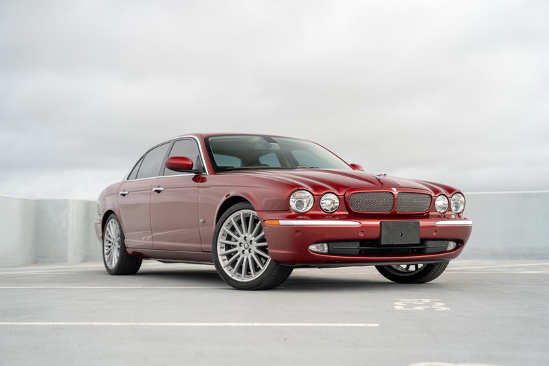 Radiant red 2006 Jaguar XJR with chrome trim and multi-spoke alloy rims.