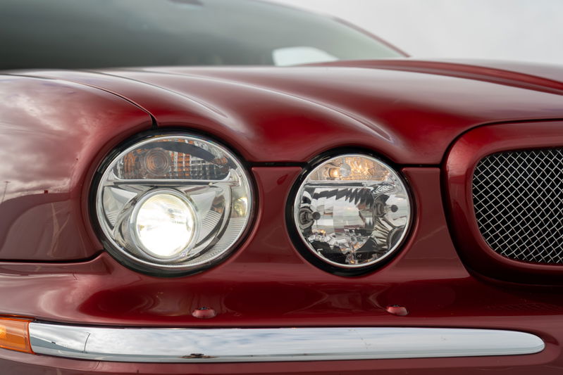 Radiance Red 2006 Jaguar XJR headlights and chrome grille detail.