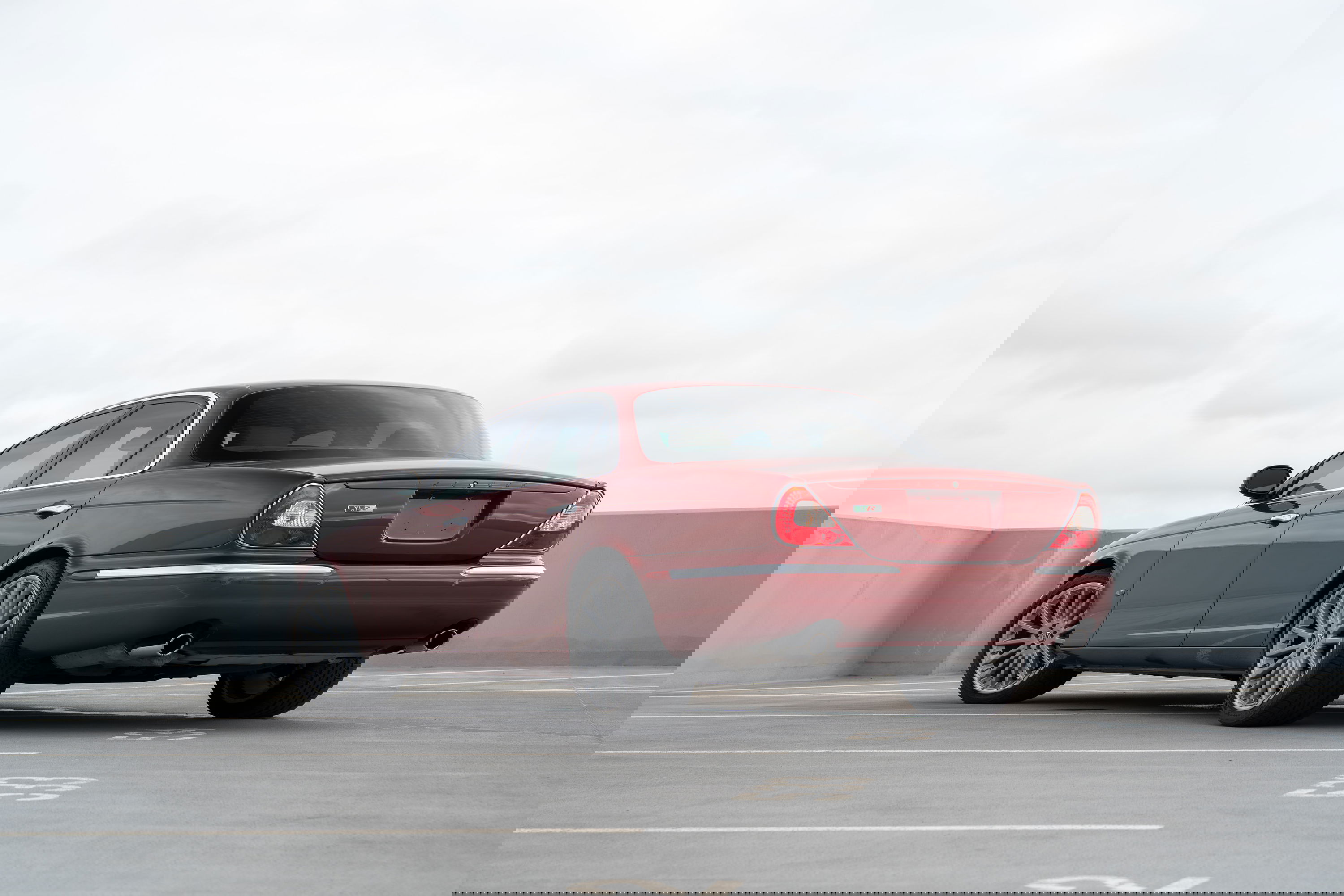 Rear view of a ruby red 2006 Jaguar XJR sedan with multi-spoke alloy rims.