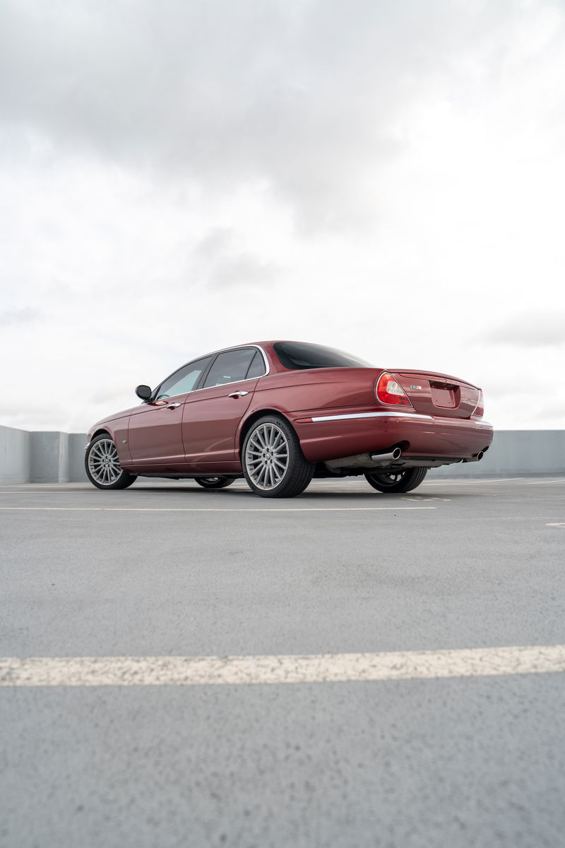 Radiance Red 2006 Jaguar XJR sedan with chrome trim and multi-spoke alloy rims.