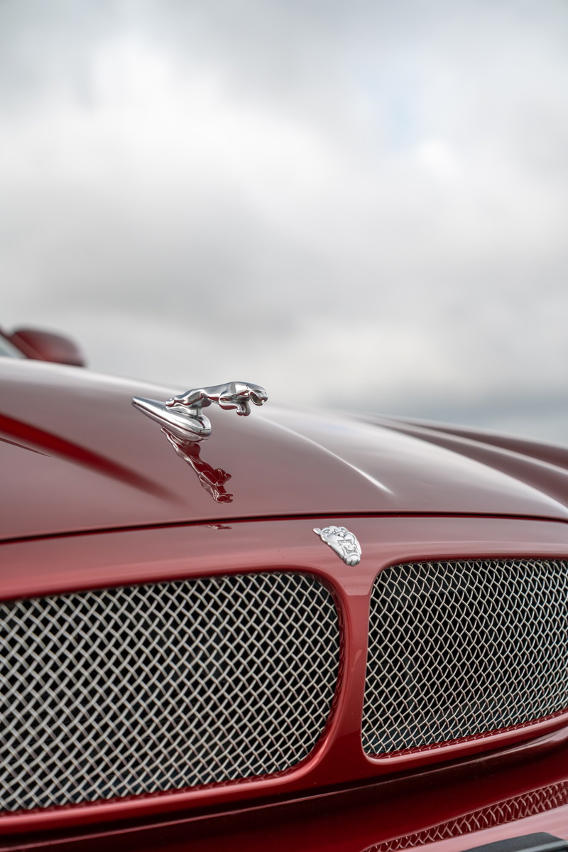 Radiance Red 2006 Jaguar XJR hood ornament and chrome grille detail.