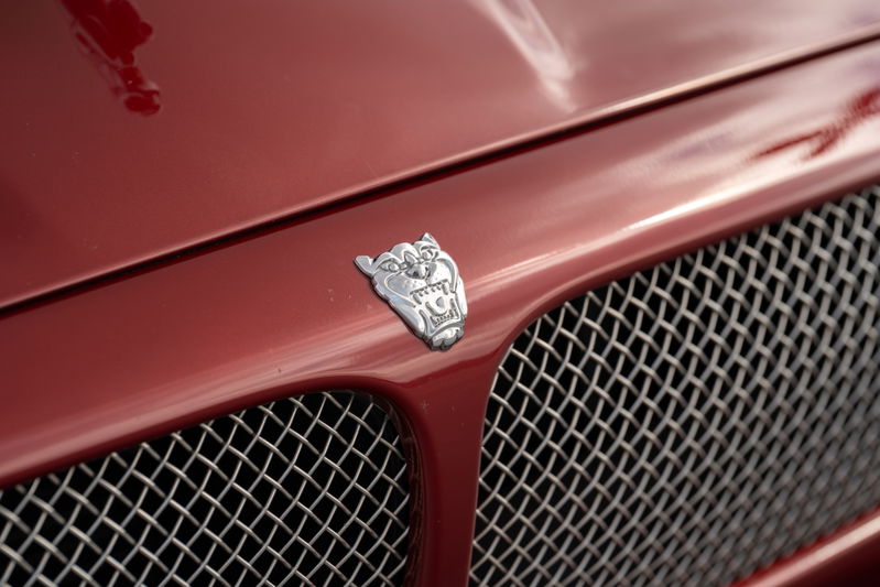 Close-up of a 2006 Jaguar XJR's chrome grille and leaping cat hood ornament. Radiance red paint.