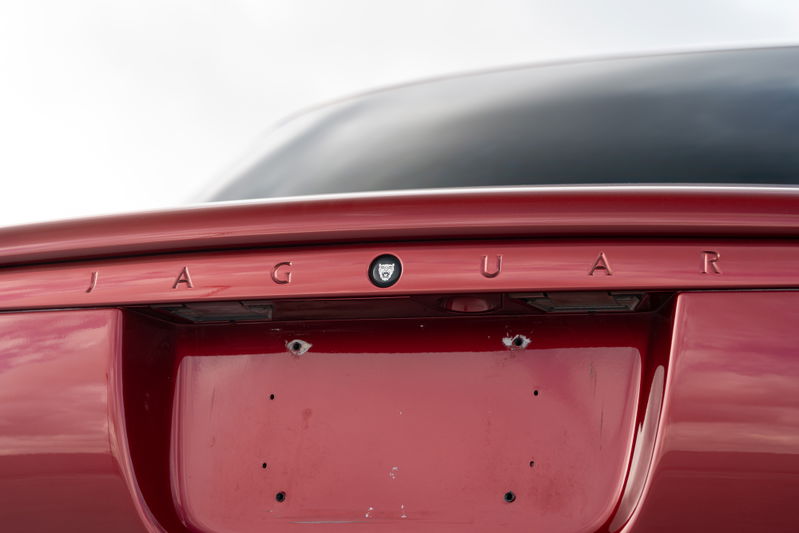 Close up of a red 2006 Jaguar XJR trunk lid with "JAGUAR" badging and license plate mounting holes.