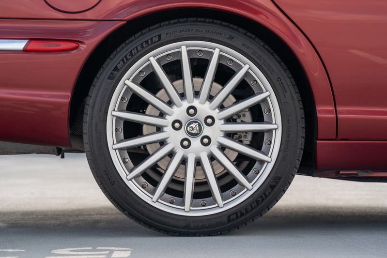 Radiance Red 2006 Jaguar XJR rear wheel with silver multi-spoke rims and Michelin Pilot Sport tires.